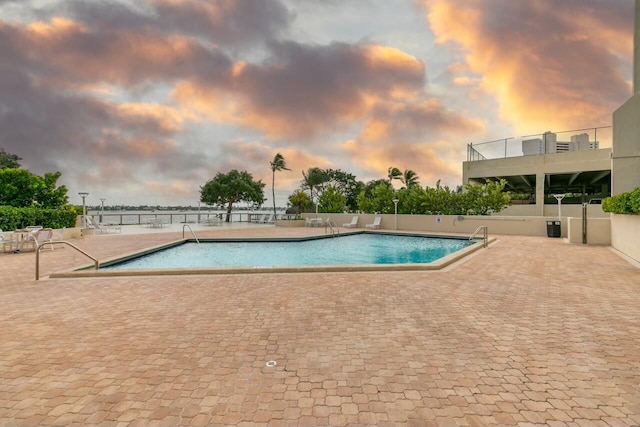 pool at dusk with a patio area