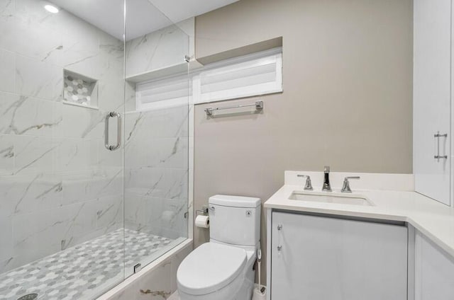 bathroom featuring vanity, a shower with shower door, and toilet