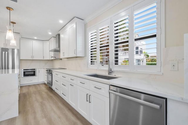 kitchen featuring white cabinetry, sink, wall chimney exhaust hood, a healthy amount of sunlight, and appliances with stainless steel finishes