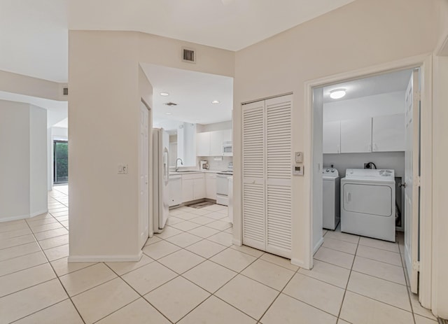 washroom featuring light tile patterned flooring, cabinets, sink, and washer and dryer