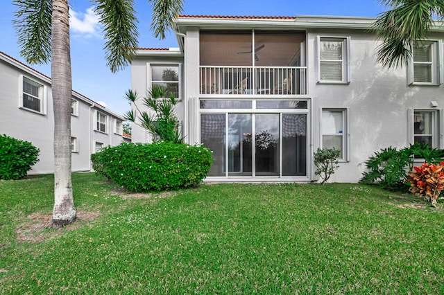 back of property with a yard and ceiling fan