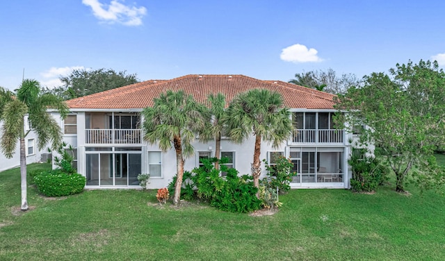 rear view of house featuring a yard and a sunroom