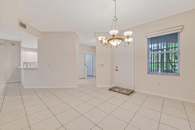 tiled entrance foyer featuring an inviting chandelier