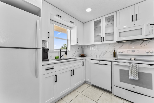 kitchen with sink, white cabinets, light tile patterned flooring, and white appliances