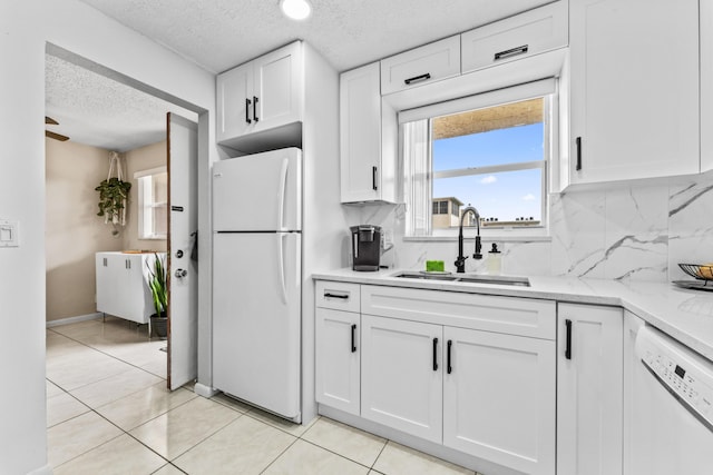 kitchen featuring sink, light tile patterned floors, a textured ceiling, white appliances, and white cabinets