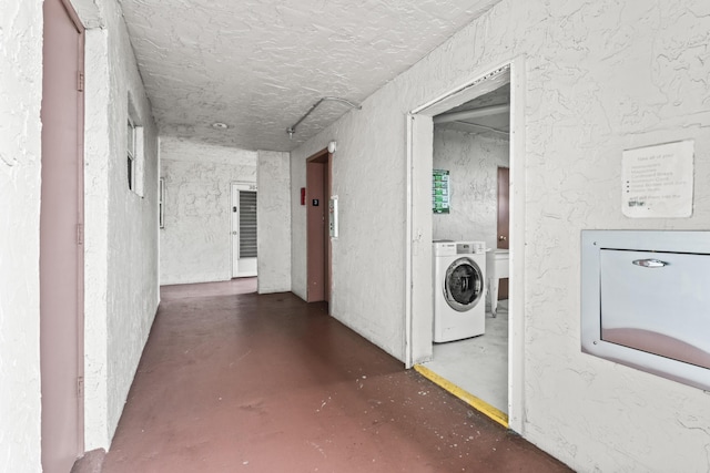 corridor featuring washer / dryer and a textured ceiling