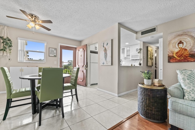 dining space with ceiling fan, light tile patterned floors, and a textured ceiling