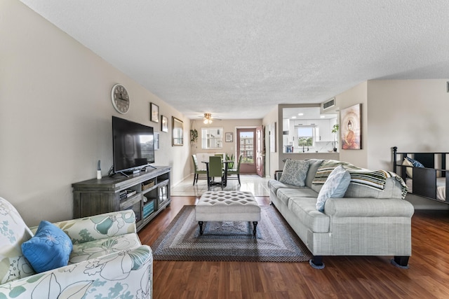 living room featuring a textured ceiling, dark hardwood / wood-style flooring, and ceiling fan