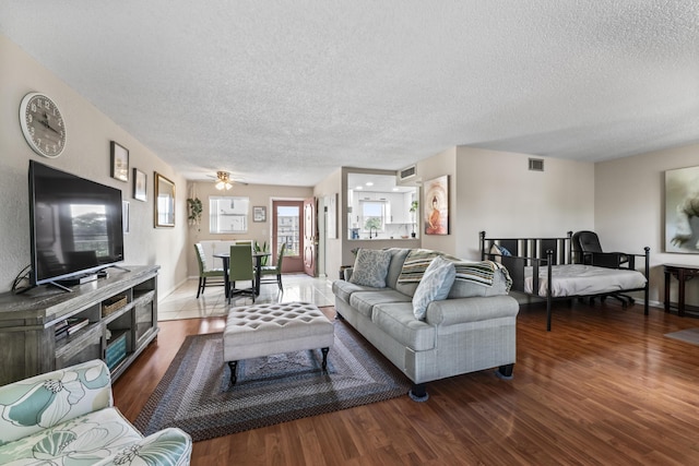 living room with a textured ceiling, dark hardwood / wood-style floors, and ceiling fan