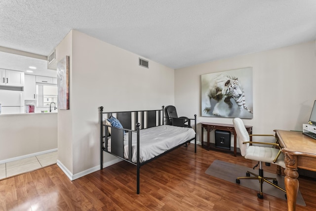 bedroom with sink, wood-type flooring, a textured ceiling, and white refrigerator