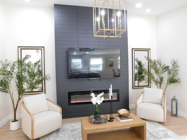 living room with wood finished floors, baseboards, recessed lighting, a fireplace, and a notable chandelier