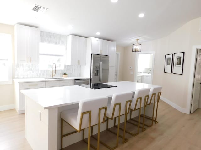 kitchen with washing machine and clothes dryer, visible vents, decorative backsplash, stainless steel appliances, and a sink