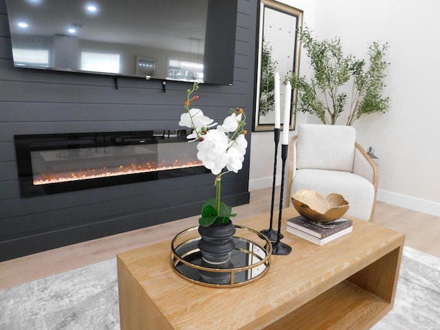 sitting room with baseboards, wood finished floors, and a glass covered fireplace