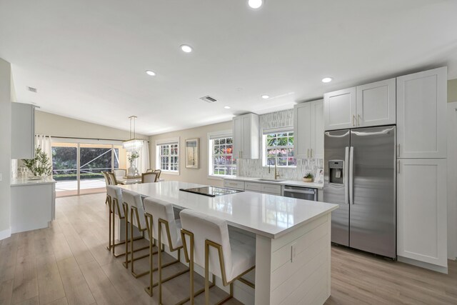 kitchen with white cabinetry, a large fireplace, light stone counters, stainless steel range oven, and decorative light fixtures