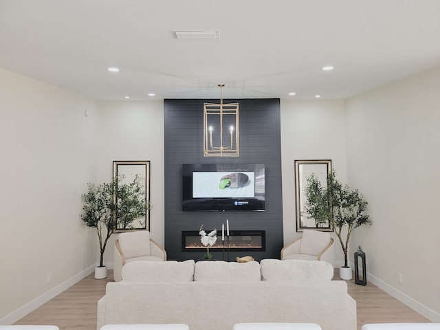 living room featuring light wood-type flooring, a large fireplace, and baseboards