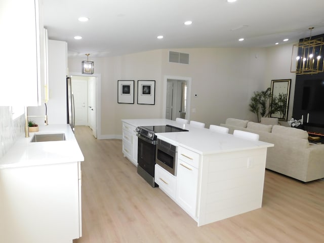 kitchen featuring stainless steel appliances, sink, light hardwood / wood-style flooring, white cabinets, and a kitchen island