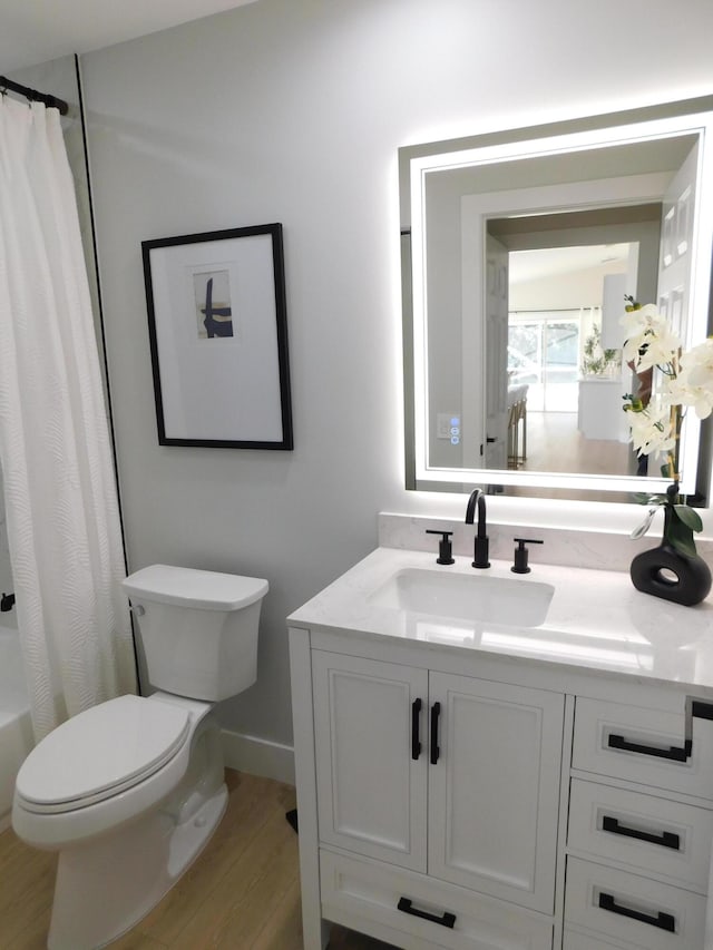 full bathroom with baseboards, toilet, wood finished floors, and vanity