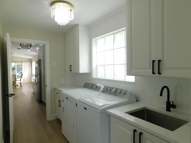 washroom with light wood-type flooring, a sink, cabinet space, separate washer and dryer, and a chandelier