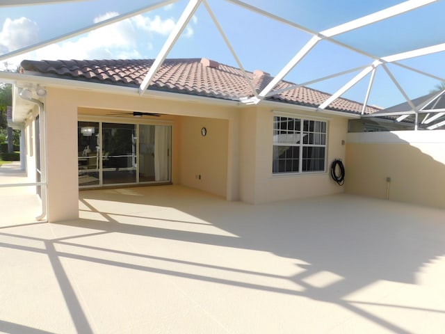 rear view of property with a patio area, glass enclosure, a tile roof, and ceiling fan