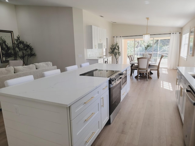 kitchen featuring a kitchen island, lofted ceiling, light wood-style floors, white cabinets, and stainless steel appliances