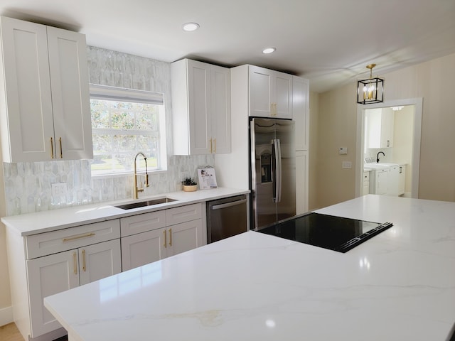 kitchen with a sink, white cabinetry, backsplash, and stainless steel appliances