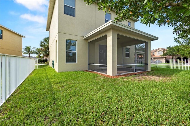 rear view of property featuring a lawn and a sunroom