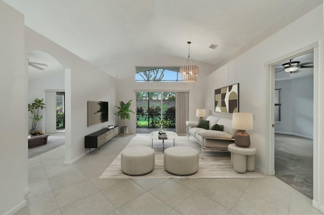 living room with ceiling fan with notable chandelier, light tile patterned flooring, and vaulted ceiling