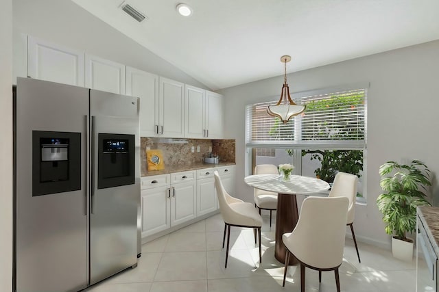 kitchen featuring stainless steel refrigerator with ice dispenser, backsplash, pendant lighting, white cabinets, and lofted ceiling