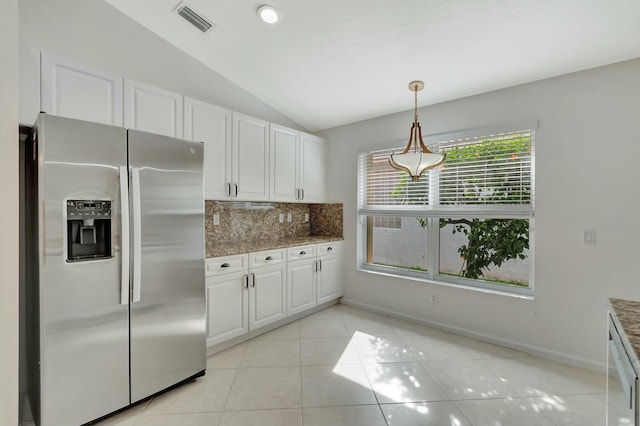 kitchen with stainless steel fridge, backsplash, vaulted ceiling, stone counters, and white cabinets