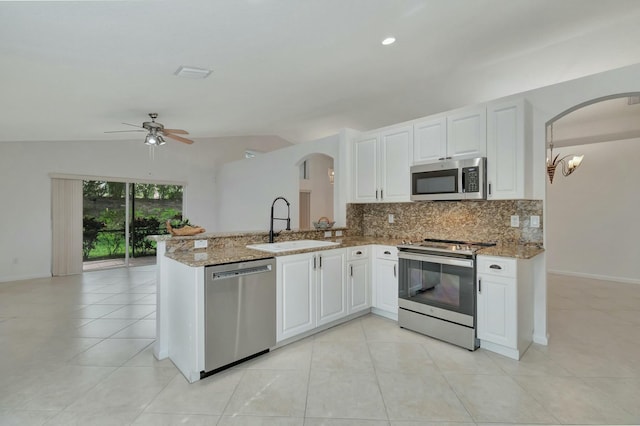 kitchen featuring white cabinets, lofted ceiling, kitchen peninsula, and appliances with stainless steel finishes