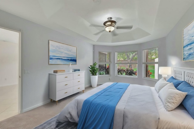 bedroom featuring ceiling fan, a raised ceiling, and light colored carpet