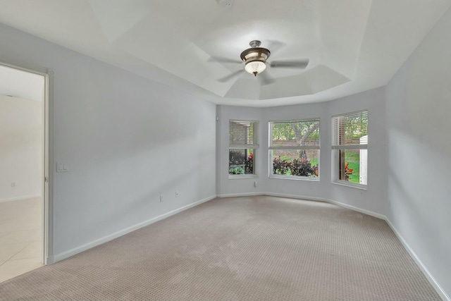 carpeted empty room with ceiling fan and a raised ceiling