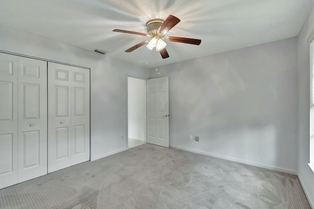 unfurnished bedroom with a closet, light colored carpet, and ceiling fan