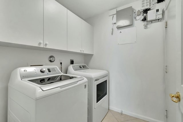 clothes washing area with cabinets, washing machine and dryer, and light tile patterned flooring