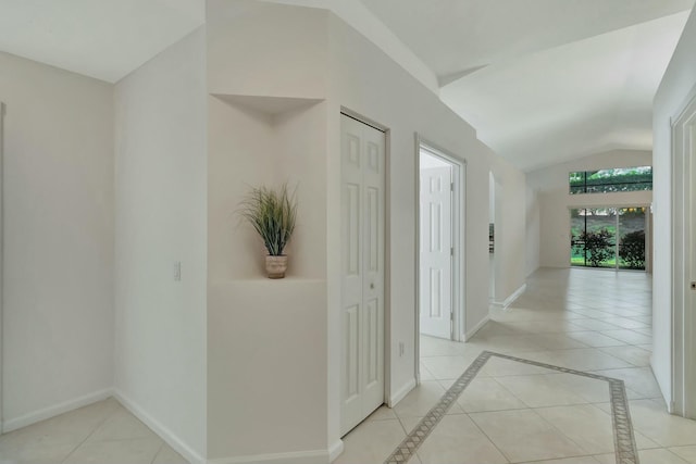 hallway featuring light tile patterned flooring and lofted ceiling