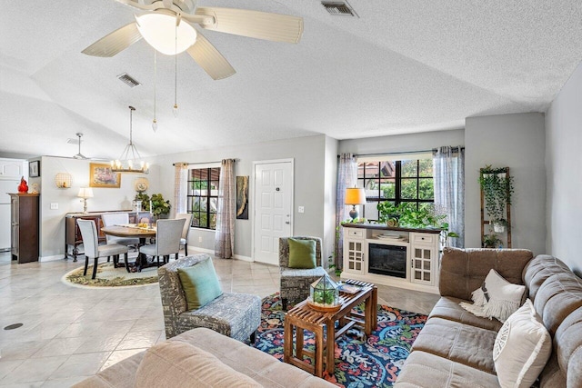 tiled living room with ceiling fan with notable chandelier and a wealth of natural light