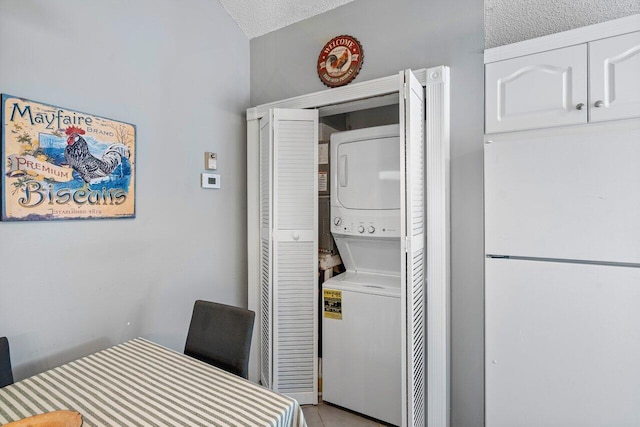 washroom featuring stacked washer / drying machine and a textured ceiling