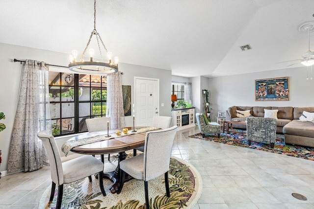 dining area with ceiling fan with notable chandelier, a textured ceiling, and vaulted ceiling