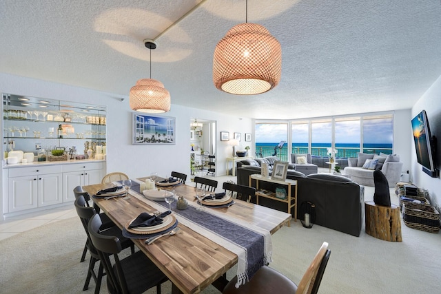 tiled dining room featuring a textured ceiling and a wall of windows