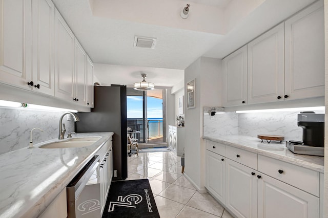 kitchen featuring sink, tasteful backsplash, white cabinets, stainless steel dishwasher, and light tile patterned flooring