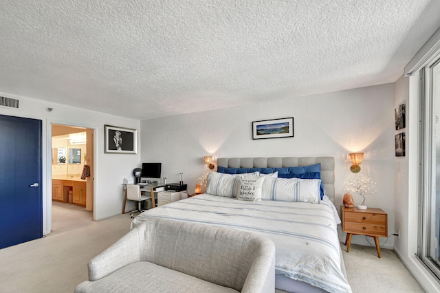 bedroom featuring ensuite bath, light carpet, and a textured ceiling