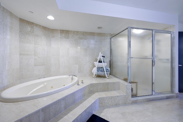 bathroom featuring shower with separate bathtub and tile walls