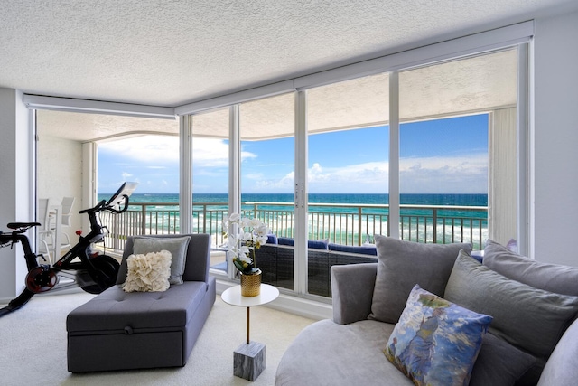 carpeted living room with a textured ceiling, a water view, and plenty of natural light