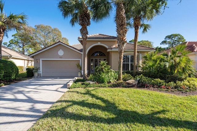 mediterranean / spanish house featuring a garage and a front yard