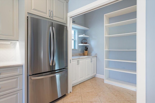 kitchen with stainless steel refrigerator, white cabinetry, tasteful backsplash, and light tile patterned floors