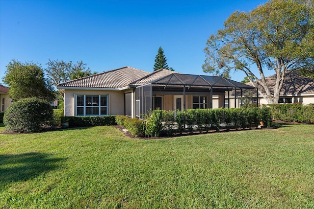 rear view of property featuring a lawn and glass enclosure