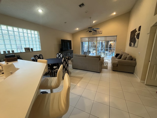 tiled living room featuring vaulted ceiling, a healthy amount of sunlight, and ceiling fan