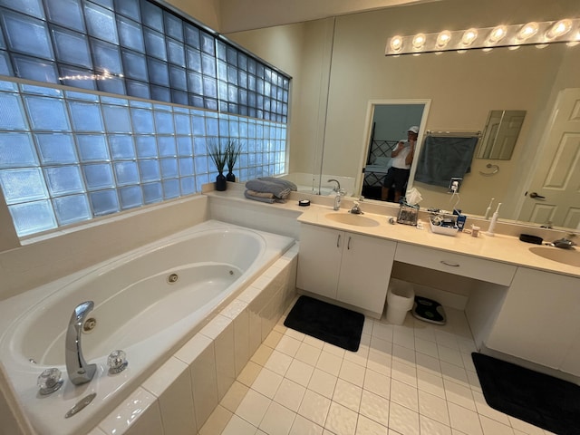 bathroom featuring tile patterned flooring, vanity, and tiled tub