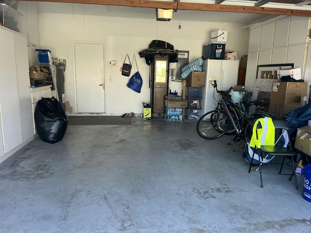 garage featuring a garage door opener and white refrigerator with ice dispenser