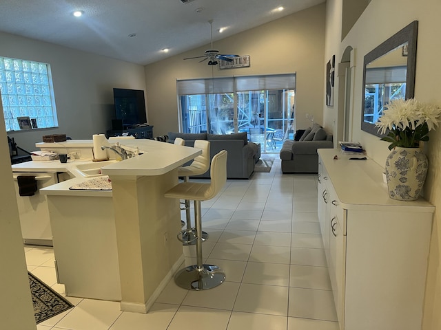 kitchen featuring light tile patterned flooring, sink, a kitchen breakfast bar, dishwasher, and white cabinets